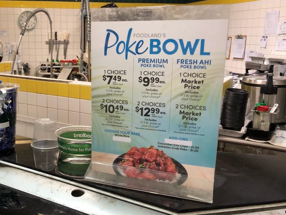 A sign at the Shack N Shave seafood counter with prices for different Poke bowl options, such as a one-choice poke bowl for $7.49 or a premium poke bowl for $9.99.