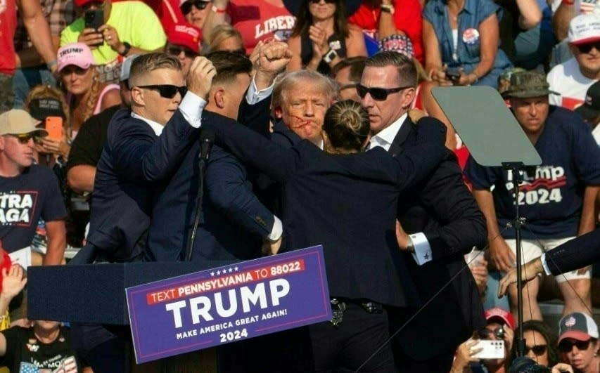 <span>Donald Trump, con el rostro ensangrentado, rodeado de agentes del Servicio Secreto durante su reunión en Butler, Pensilvania, el 13 de julio de 2024</span><div><span>Rebecca DROKE</span><span>AFP</span></div>