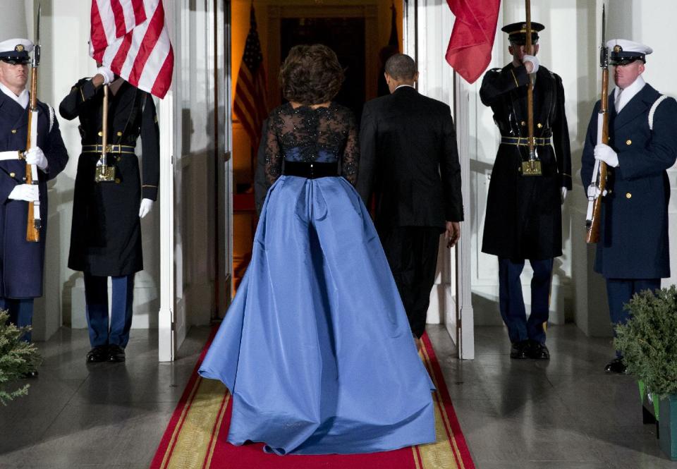 La primera dama Michelle Obama, en un vestido de Carolina Herrera, y el presidente Barack Obama, entran a la Casa Blanca tras recibir al presidente francés François Hollande para una cena de estado, el martes 11 de febrero del 2014 en Washington. (AP Foto/Evan Vucci)