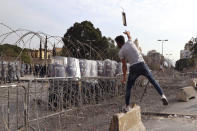 A protester throws an object towards riot police during a protest against French President Macron's comments over Prophet Muhammad caricatures, near the Pine Palace, which is the residence of the French ambassador, in Beirut, Lebanon, Friday, Oct. 30, 2020. A few hundred demonstrators held a protest called for by a Sunni Islamist party, Hizb ul-Tahrir, against French cartoons of the Prophet Muhammad. (AP Photo/Bilal Hussein)