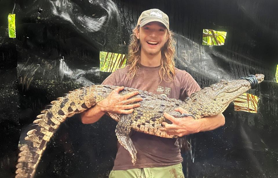Parker Gibbons holds a 6-foot-long Morelet’s crocodile captured during a research project in Central America.