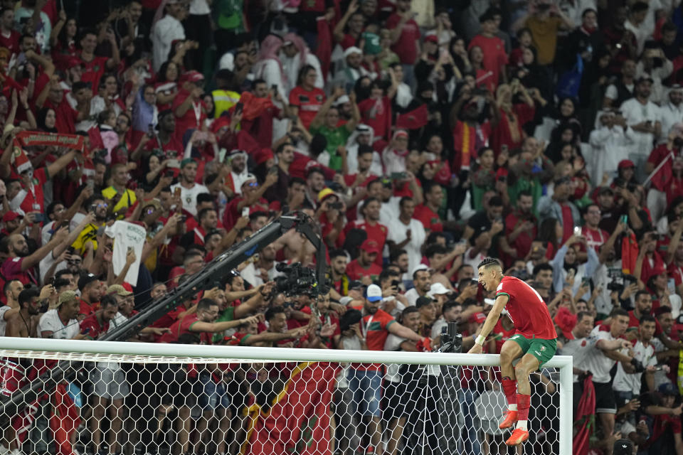 Morocco's Jawad El Yamiq climbs on the crossbar as he celebrates his team's victory during the World Cup round of 16 soccer match between Morocco and Spain, at the Education City Stadium in Al Rayyan, Qatar, Tuesday, Dec. 6, 2022. (AP Photo/Ebrahim Noroozi)