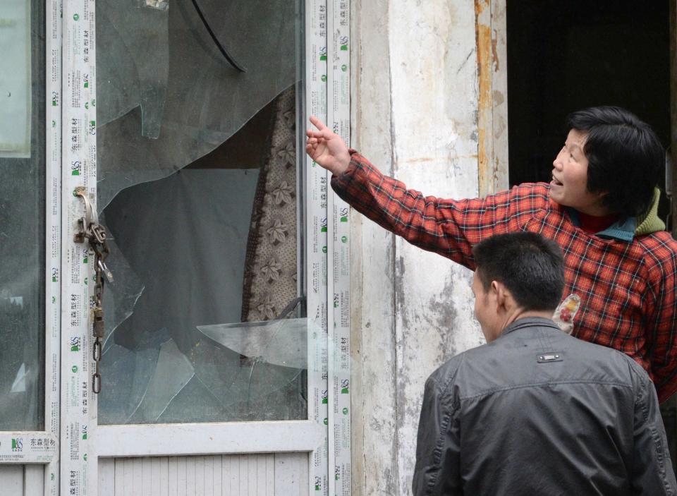 A woman points to a broken window at a building, which was damaged by an explosion in Urumqi on Thursday, in the Xinjiang Uighur Autonomous Region, in this photo taken by Kyodo on May 22, 2014. Five suicide bombers carried out the attack which killed 31 people in the capital of China's troubled Xinjiang region, state media reported a day after the deadliest terrorist attack to date in the region. Picture taken May 22, 2014. Mandatory credit REUTERS/Kyodo (CHINA - Tags: CRIME LAW CIVIL UNREST POLITICS) ATTENTION EDITORS - THIS IMAGE HAS BEEN SUPPLIED BY A THIRD PARTY. FOR EDITORIAL USE ONLY. NOT FOR SALE FOR MARKETING OR ADVERTISING CAMPAIGNS. MANDATORY CREDIT. JAPAN OUT. NO COMMERCIAL OR EDITORIAL SALES IN JAPAN. THIS PICTURE IS DISTRIBUTED EXACTLY AS RECEIVED BY REUTERS, AS A SERVICE TO CLIENTS. YES