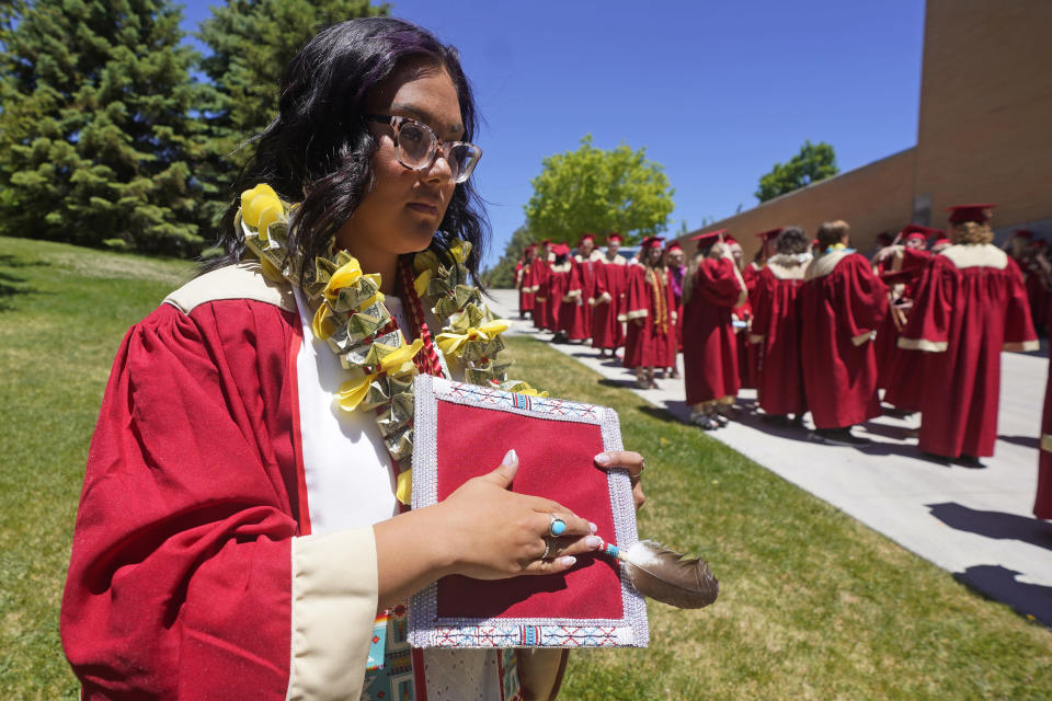 Amryn Tom holds her beaded graduation cap and eagle feather during her graduation from Cedar City High School on Wednesday, May 25, 2022, in Cedar City, Utah. Tom is wearing an eagle feather given to her by her mother and a cap that a family friend beaded. (AP Photo/Rick Bowmer)