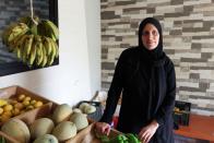 Khadija Shreim stands near her vegetables and fruits stall in Houla village