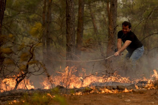 A man tries to extinguish a fire near the Cardak neighbourhood of Manavgat district of Antalya, Turkey.  (Photo: Anadolu Agency via Getty Images)