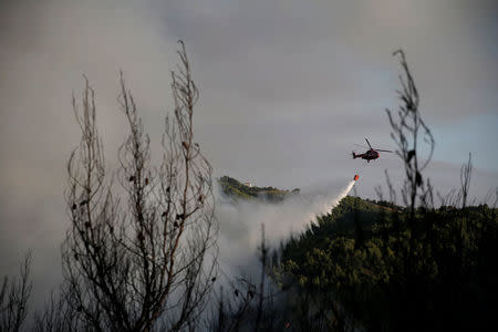 A firefighting helicopter makes a water drop as a wildfire burns near the village of Metochi, north of Athens, Greece, August 14, 2017. REUTERS/Alkis Konstantinidis