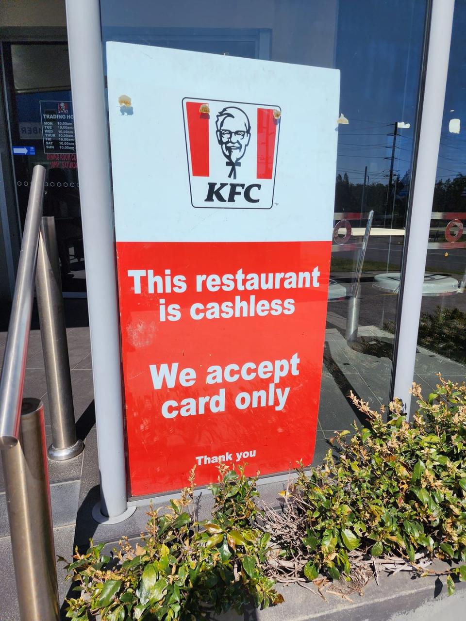 A sign is posted in the window of a KFC advising cash will not be accepted.