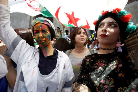 Demonstrators with painted faces hold flags during anti government protests in Algiers, Algeria April 23, 2019. The writing on the neck reads "Algeria is protected by people". REUTERS/Ramzi Boudina