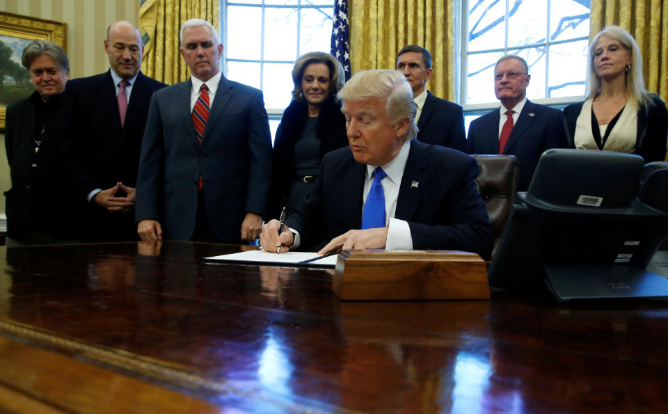 U.S. President Donald Trump signs a memorandum to security services directing them to defeat the Islamic State in the Oval Office at the White House in Washington, U.S. January 28, 2017. Pictured with him are White House senior advisor Steve Bannon (L-R), National Economic Council Director Gary Cohn, Vice President Mike Pence, Deputy National Security Advisor K. T. McFarland, National Security Advisor Michael Flynn, National Security Council Chief of Staff Keith Kellogg and senior advisor Kellyanne Conway. REUTERS/Jonathan Ernst TPX IMAGES OF THE DAY