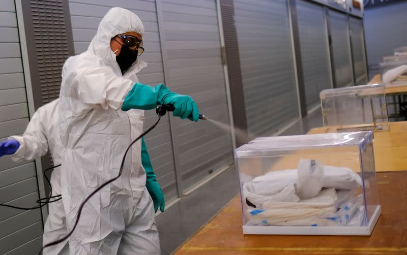 Un trabajador usa desinfectante para limpiar las urnas que contienen los equipos de protección individual en el mercado de Sant Antoni, un colegio electoral para los comicios autonómicos del 14 de febrero, durante el brote de la enfermedad del coronavirus (COVID-19) en Barcelona, España.