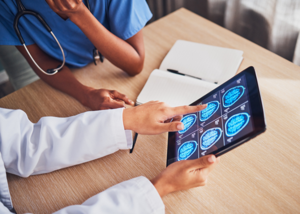 Two medical professionals looking at a brain scan on a tablet.