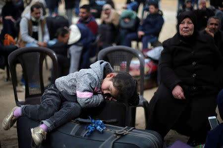 A girl sleeps on a suitcase as she waits with her family for a travel permit to cross into Egypt through the Rafah border crossing after it was opened by Egyptian authorities for humanitarian cases, in the southern Gaza Strip February 8, 2018. REUTERS/Ibraheem Abu Mustafa