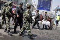 Heavily armed Chinese paramilitary policemen march past the site of the Wednesday's explosion outside the Urumqi South Railway Station in Urumqi in northwest China's Xinjiang Uygur Autonomous Region Thursday, May 1, 2014. Chinese President Xi Jinping has demanded 'decisive actions" against terrorism following the attack at the railway station in the far west minority region of Xinjiang that left three people dead and 79 injured. (AP Photo/Ng Han Guan)