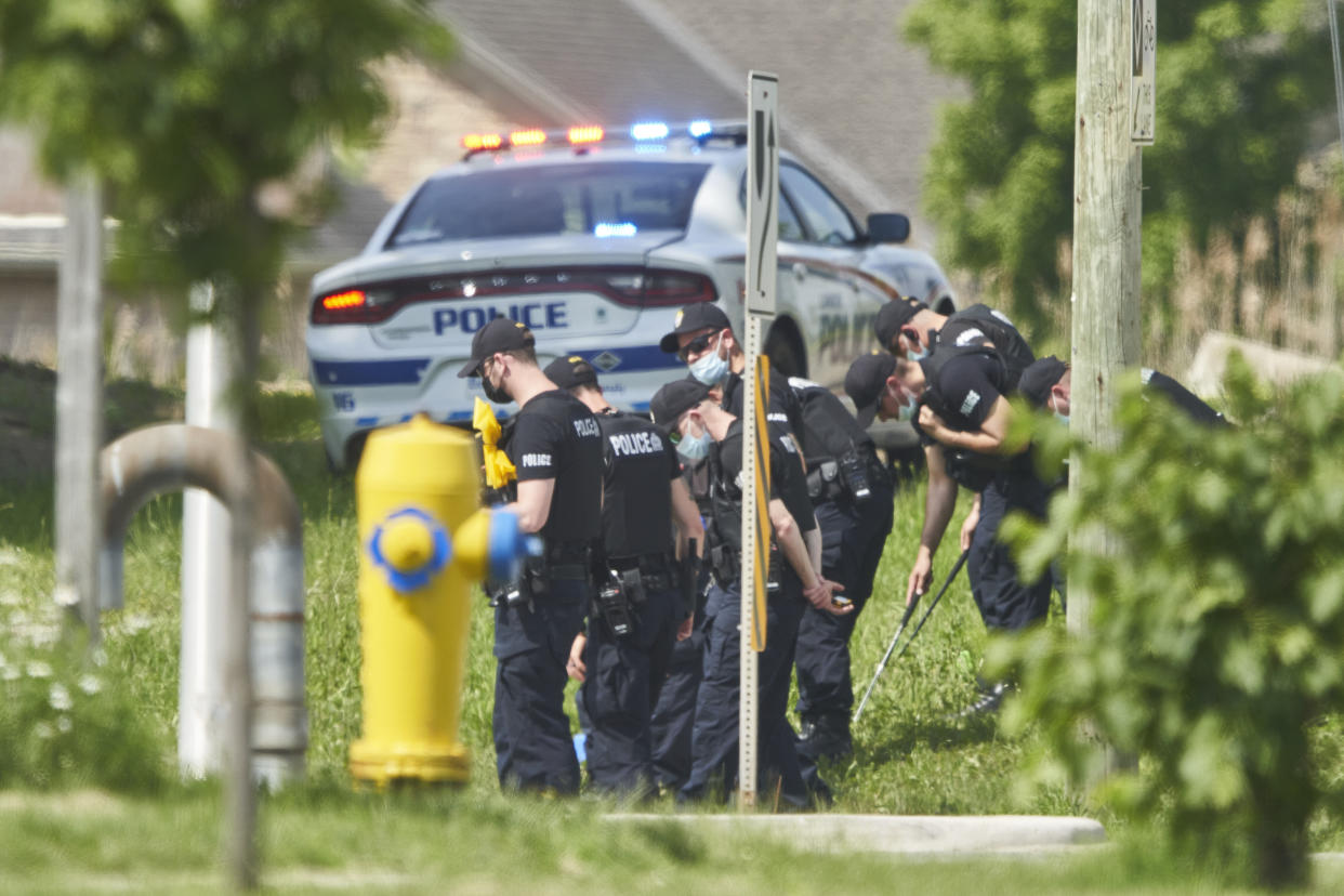 A line of police officers look for evidence at the scene of a car crash in London, Ontario on Monday, June 7, 2021. Police say multiple people have died after several pedestrians were struck by a car Sunday night. (Geoff Robins/The Canadian Press via AP)