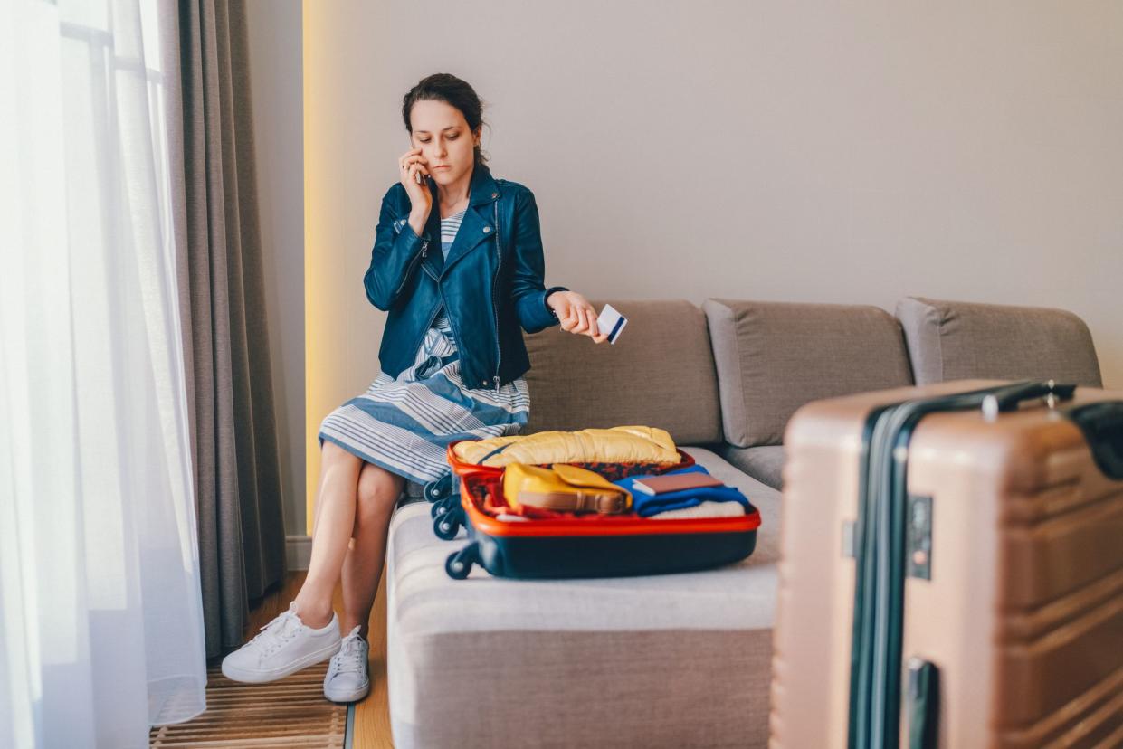 Young woman in hotel room trying to call the bank for customer support