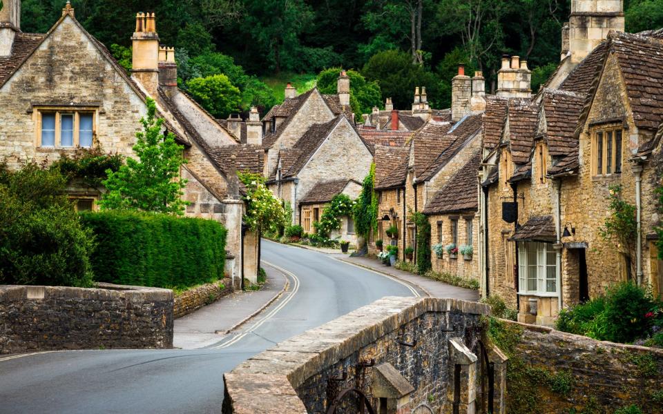 Traditional English village in the Cotswolds area of southwest England. The cosy little brick cottages line the narrow road, and there is also a quaint bridge spanning a little stream