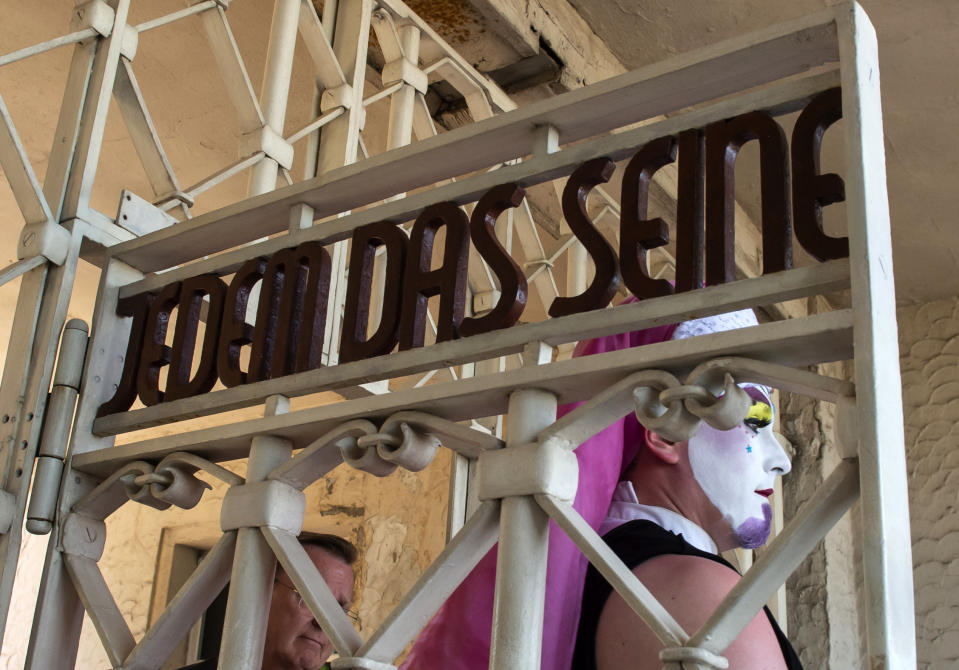 People arrive at the camp entrance with the slogan 'To Each His Own' (Jedem das Seine) in remembrance of prisoners assigned a pink triangle in the former Nazi concentration camp Buchenwald within the Christopher Street Day in Weimar, Germany, Sunday, June 23, 2019. There were 650 prisoners assigned a pink triangle in the Buchenwald concentration camp between 1937 and 1945. Many of them lost their lives. (AP Photo/Jens Meyer)