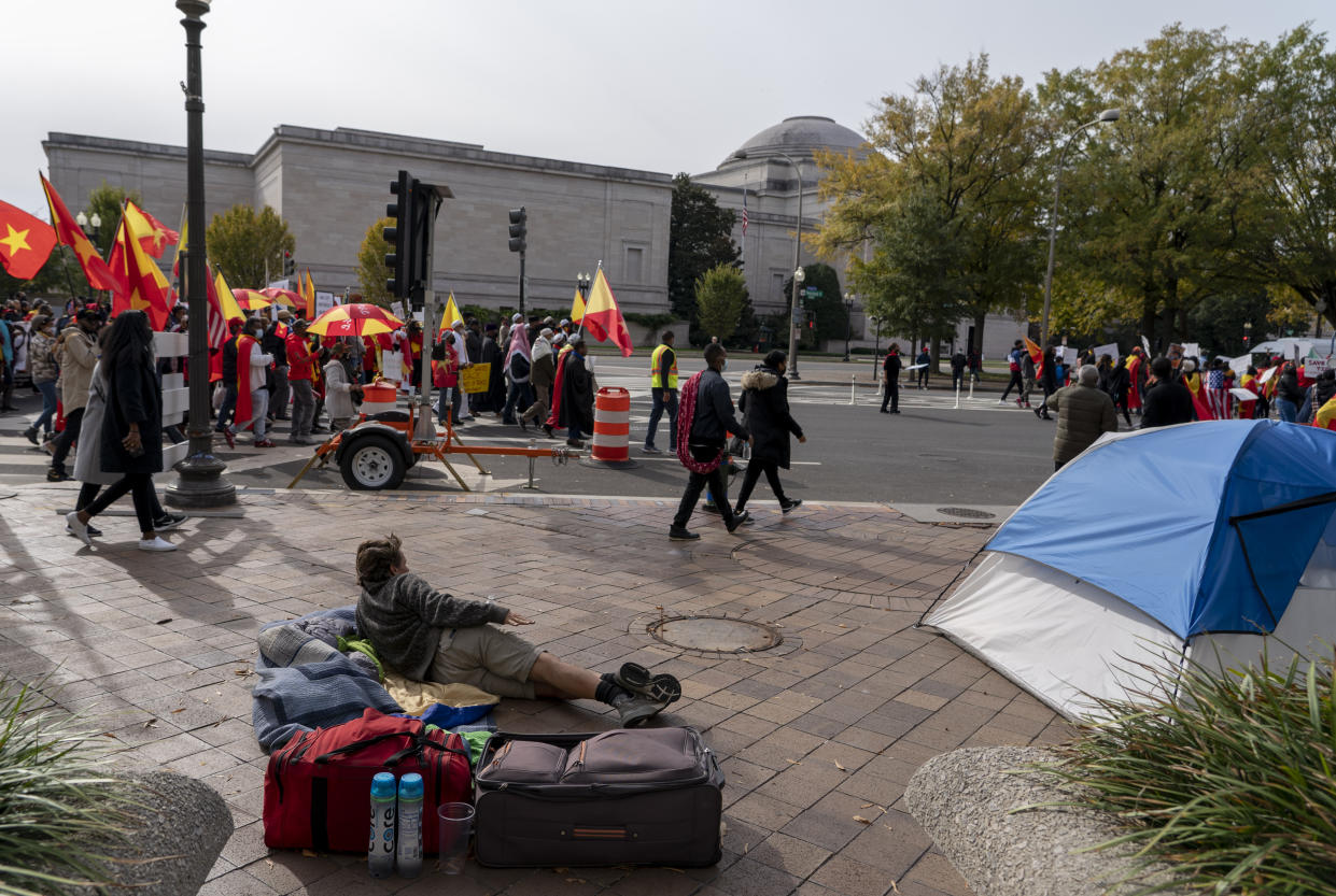 A homeless man watches as exile Tigray community and their supporters march to mark a year since Ethiopia Prime Minister Abiy Ahmed's administration started fighting against the Tigray, the northernmost region in Ethiopia, at the U.S. Capitol, Thursday, Nov. 4, 2021, in Washington. (AP Photo/Gemunu Amarasinghe)