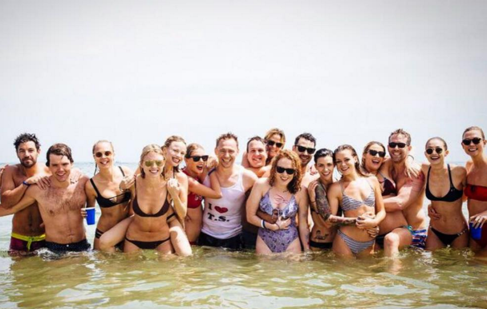 Of course Tom wore a “I  T.S.” tank for a frolic in the water with Taylor. Here they are, front and center, posing with all the party guests — like they are prom queen and king. (Photo: Instagram)