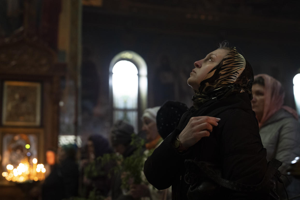 A woman makes the sign of the cross during an Orthodox Palm Sunday service at a church.