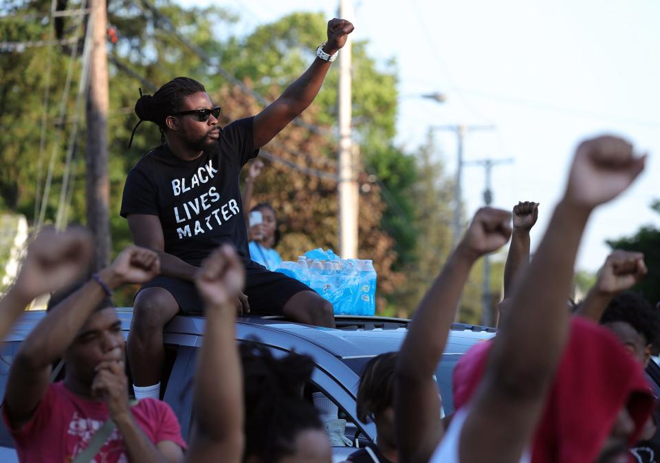 Protesters raise their fists during a moment of silence for Jayland Walker at Buchtel High School, Sunday, July 3, 2022, in Akron, Ohio.