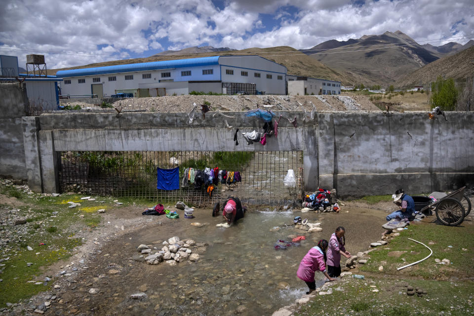 Women wash clothes in a stream near an industrial area in a village outside of Lhasa in western China's Tibet Autonomous Region, as seen during a rare government-led tour of the region for foreign journalists, Wednesday, June 2, 2021. Long defined by its Buddhist culture, Tibet is facing a push for assimilation and political orthodoxy under China's ruling Communist Party. (AP Photo/Mark Schiefelbein)