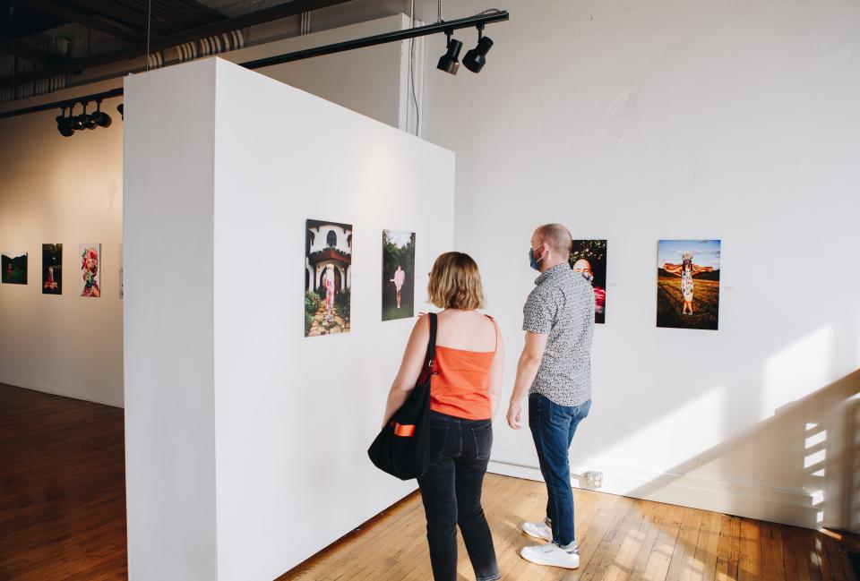 Visitors look at photographs at a First Friday show at the Emporium in 2021.