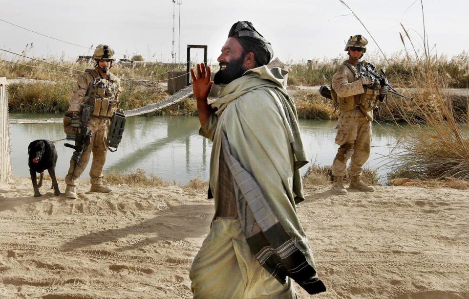 Marine Cpl Jeffrey De Young, of Holland, MI and LCpl Gamble, Sugarland, Texas watch an Afghan man walk past them as they start the days patrol outside the wire at FOB Hassanabad.