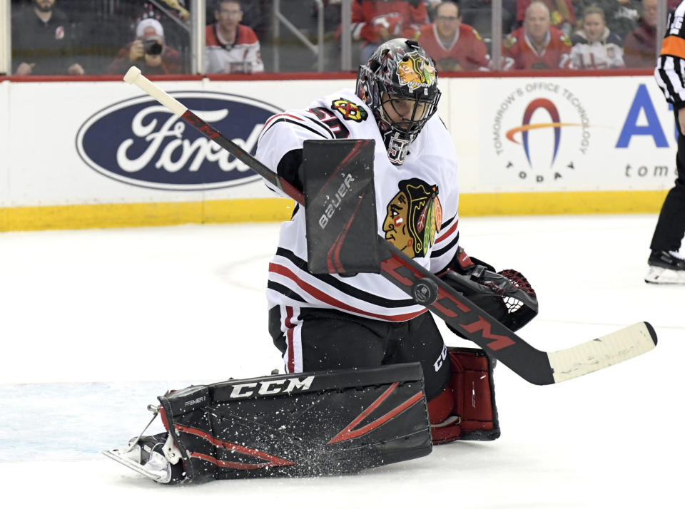 Chicago Blackhawks goaltender Corey Crawford (50) deflects the puck during the second period of an NHL hockey game against the New Jersey Devils, Friday, Dec. 6, 2019, in Newark, N.J. (AP Photo/Bill Kostroun)