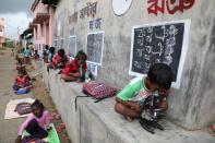 Children use microscopes as they attend an open-air class outside houses with the walls converted into black boards at Joba Attpara village