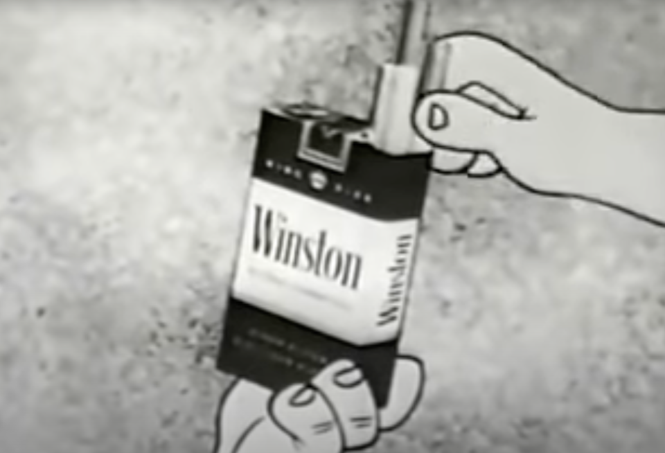 A vintage cartoon hand holds a pack of Winston cigarettes, with a cigarette being taken from the pack. The pack's text reads 