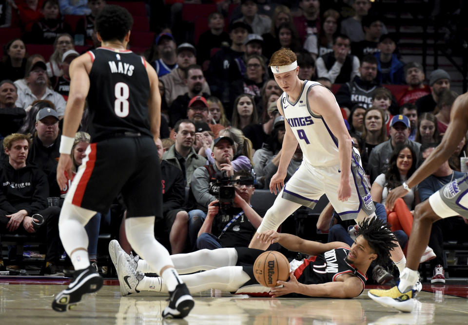 Portland Trail Blazers guard Shaedon Sharpe, bottom, falls to the floor to go after the ball as Sacramento Kings guard Kevin Huerter, top, looks on during the first half of an NBA basketball game in Portland, Ore.,Friday, March 31, 2023. (AP Photo/Steve Dykes)