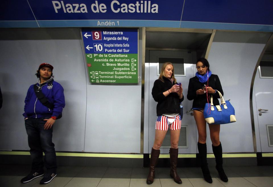 Passengers without their pants check their mobile phones as they wait for a train during the "No Pants Subway Ride" event in Madrid