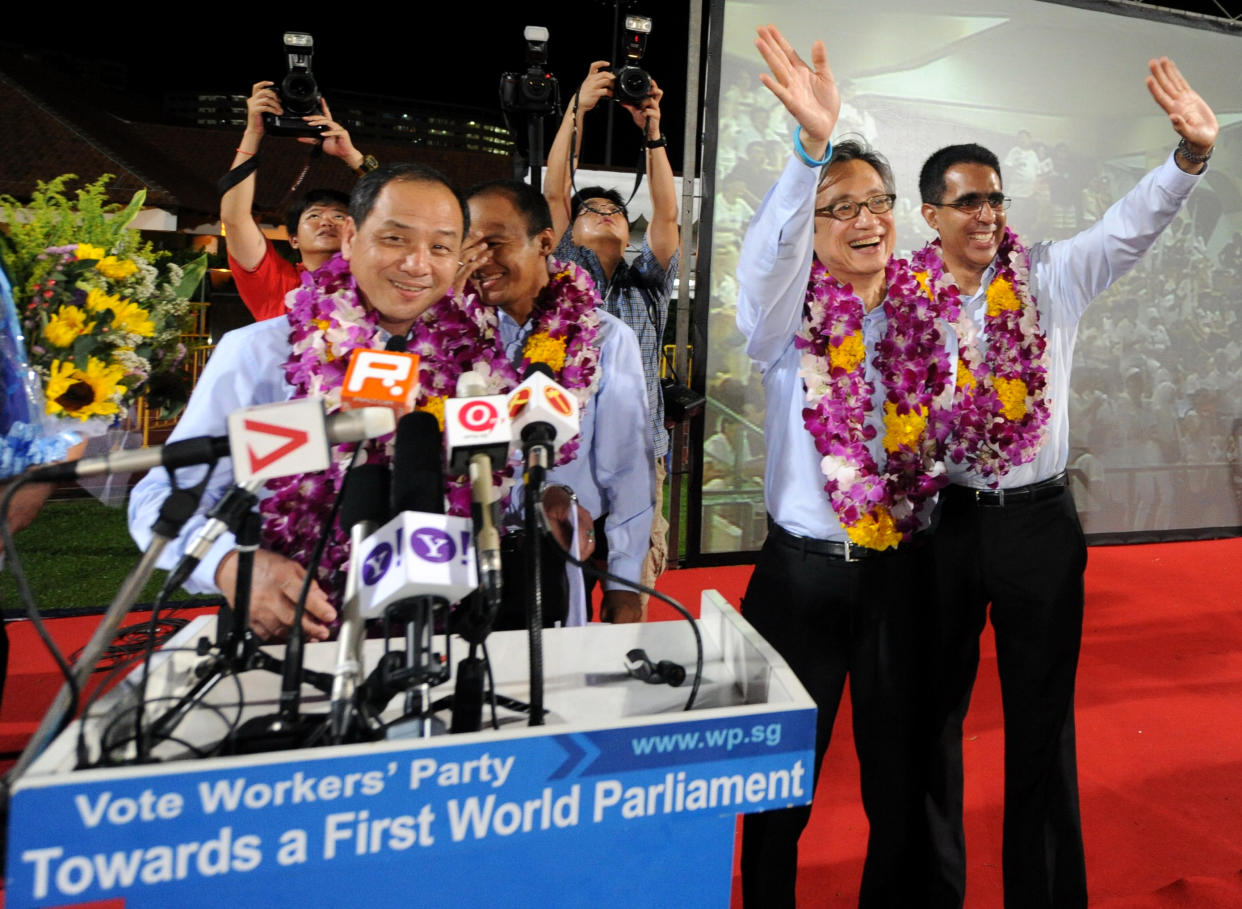 Low Thia Khiang (left) of opposition Workers' Party smiles while Chen Show Mao (second from right) and Pritam Singh (right), candidates of the party for the 2011 general election, wave to supporters as they celebrate winning Aljunied GRC. (AFP via Getty Images file photo)