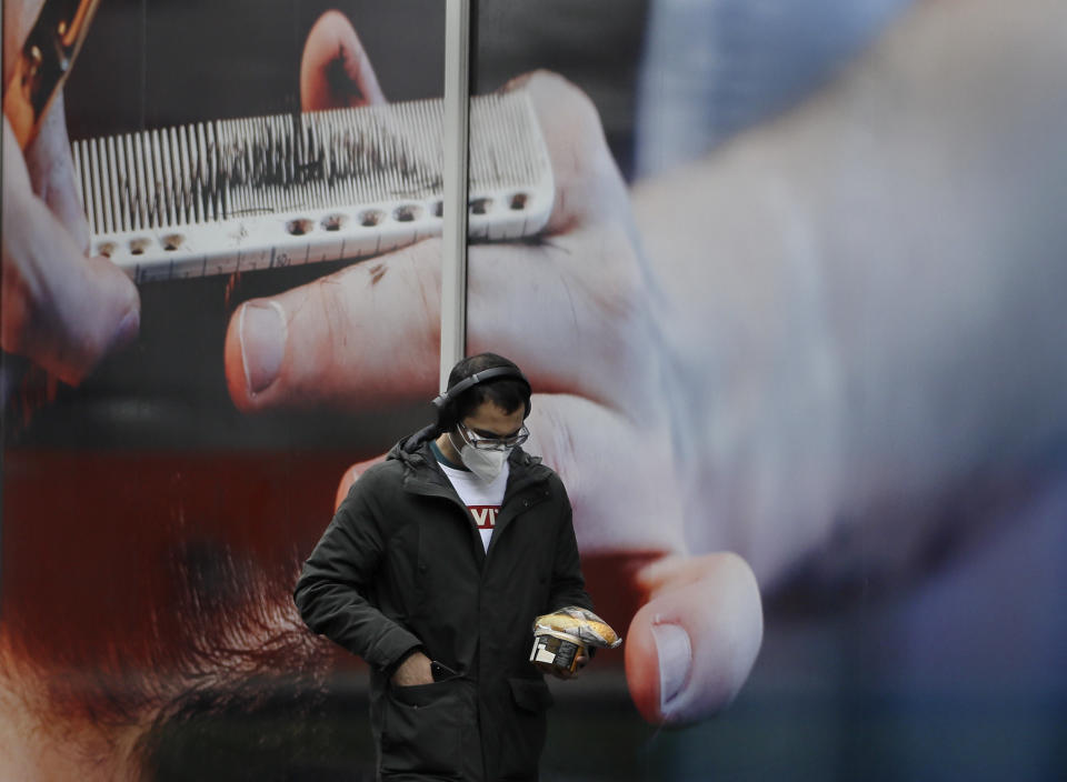 A man passes an advert on a retail premises in London, Tuesday, Oct. 27, 2020. The British government is sticking to its strategy of tiered, regional restrictions to combat COVID-19 amid mounting political and scientific pressure for stronger nationwide measures to prevent the pandemic from spiralling out of control. (AP Photo/Kirsty Wigglesworth)