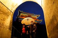 People wearing face masks walk through an ancient city wall in Jingzhou