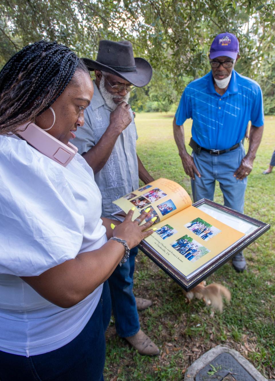 From right, Gus Rich looks on as Charles Smith and Kasey Cunningham look through a photo book while discussing family history along Persimmon Hollow Road in Milton on Friday, Aug. 18, 2023.