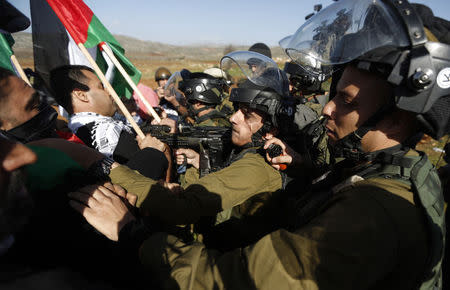 Israeli soldiers scuffle with Palestinians during a protest against Jewish settlements near the West Bank city of Ramallah December 10, 2014. REUTERS/Mohamad Torokman