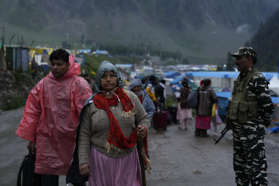 An Indian soldier stands guard as Hindu pilgrims return back after the cloudburst at Baltal, 105 kilometers (65miles) northeast of Srinagar, Indian controlled Kashmir, Saturday, July 9, 2022. More than ten pilgrims have been killed and many feared missing after a cloudburst triggered a flash flooding during an annual Hindu pilgrimage to an icy Himalayan cave in Indian-controlled Kashmir. Officials say the cloudburst near the hollowed mountain cave revered by Hindus on Friday sent a wall of water down a mountain gorge and swept about two dozen encampments and two makeshift kitchens. (AP Photo/Mukhtar Khan)