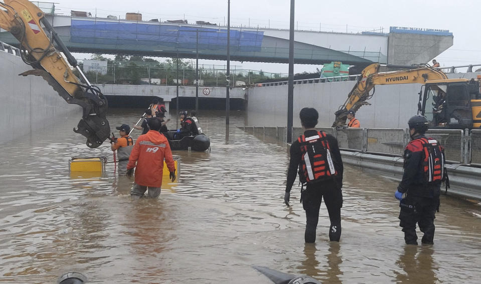In this photo provided by South Korea National Fire Agency, rescuers search for survivors along a road submerged by floodwaters leading to an underground tunnel in Cheongju, South Korea, Sunday, July 16, 2023. Days of heavy rain triggered flash floods and landslides and destroyed homes, leaving scores of people dead and forcing thousands to evacuate, officials said Sunday. (South Korea National Fire Agency via AP)