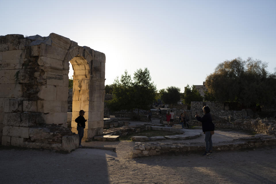 A tourist poses at the ancient building of Hadrian's Library, in central Athens, on Friday, Oct. 7, 2022.The tourism industry in Greece and Portugal are expected to make a full recovery from the pandemic, while other EU members in the Mediterranean have also performed above the expectations of national governments. (AP Photo/Petros Giannakouris)