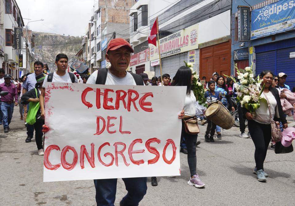 A man walks holding a sign with a message that reads in Spanish: "Shut down Congress," in the funeral procession of Clemer Rojas, 23, who was killed during protests against new President Dina Boluarte, in Ayacucho, Peru, Saturday, Dec. 17, 2022. The eight deaths this week that converted Ayacucho into the epicenter of violence in Peru's still unfolding crisis is for many a stark reminder of the region's bloody past and longstanding neglect by authorities in the far-away capital. (AP Photo/Franklin Briceno)