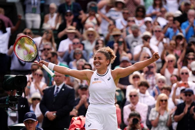 Jasmine Paolini holds her arms out wide in celebration as the crowd rise to applaud her