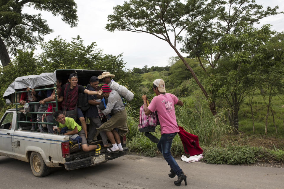 In this Nov. 2, 2018 photo, a member of about 50 LGBTQ migrants hoping to reach the U.S. border, chases after an overloaded pickup in hopes of hitching a ride to Donaji, Mexico. Much of the trek has been covered on foot, but hitching rides in the beds of pickups, minibuses and tractor-trailers has been crucial, especially on days when they travel 100 miles or more. For the LGBTQ group, it's been tougher to find those rides. (AP Photo/Rodrigo Abd)