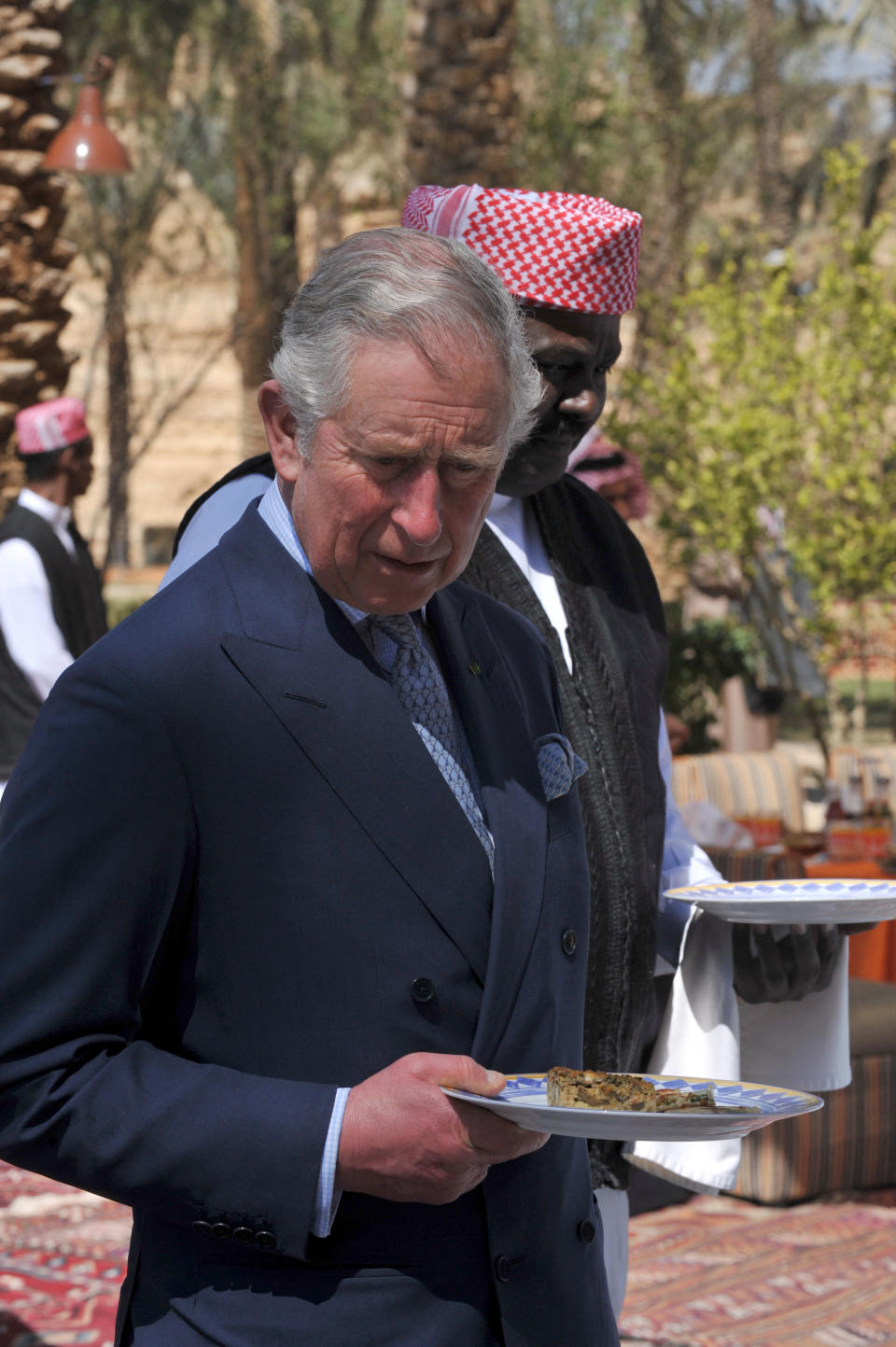 Britain's Prince Charles holds a plate in front of a buffet during a lunch break on February 19, 2014 as part of a visit at an historical site in al-Diriyah on the northwestern outskirts of the Saudi capital, Riyadh. Charles is in Saudi Arabia on a private visit.  AFP PHOTO/ POOL / FAYEZ NURELDINE (Photo by Fayez Nureldine / POOL / AFP) (Photo by FAYEZ NURELDINE/POOL/AFP via Getty Images)