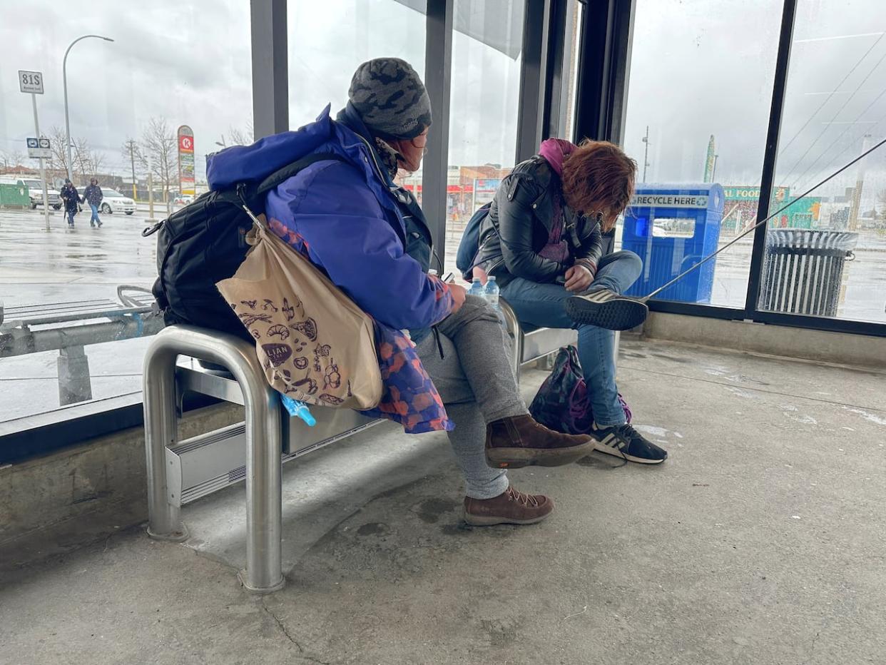 Alysha, pictured left, seeks shelter from the rain at the Chinook transit station. She says she's been sleeping in a river valley camp and gets frustrated when peace officers on transit are constantly telling her to move on. She asked to use her first name only. (Elise Stolte/CBC - image credit)