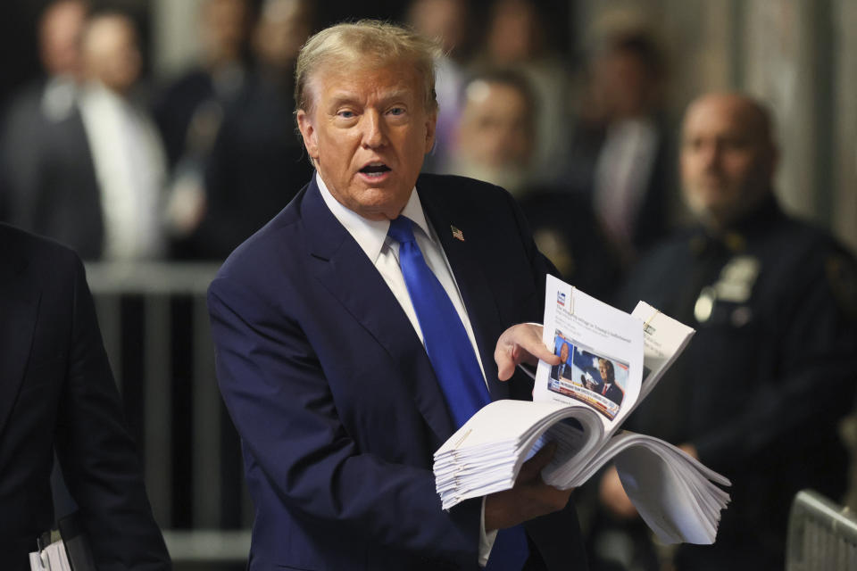 Former President Donald Trump speaks with the media while holding news clippings following his trial at Manhattan criminal court in New York on Thursday, April 18, 2024. (Brendan McDermid/Pool Photo via AP)