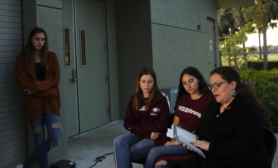 In this Wednesday, Jan. 16, 2019, photo, Brianna Jesionowski, from far left to right, Brianna Fisher and Leni Steinhardt attend an interview with The Associated Press as journalism teacher Sarah Lerner, right, reads from a new book called "Parkland Speaks: Survivors from Marjory Stoneman Douglas Share Their Stories," in Parkland, Fla. Students and teachers from the Florida school where 17 died in February’s high school massacre wrote the raw, poignant book about living through the tragedy. (AP Photo/Brynn Anderson)