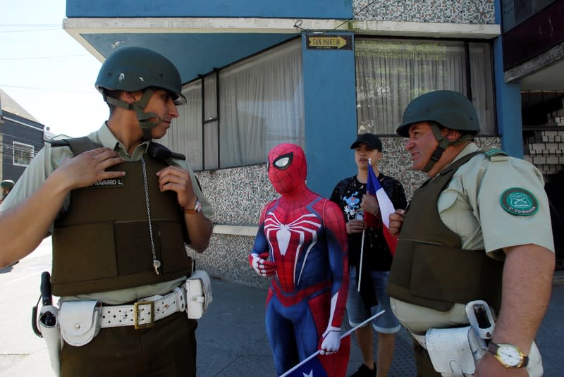 A demonstrator, wearing a costume of comics superhero Spiderman, chats with officers of the Chilean police (Carabineros) during a protest against social inequality in Concepcion